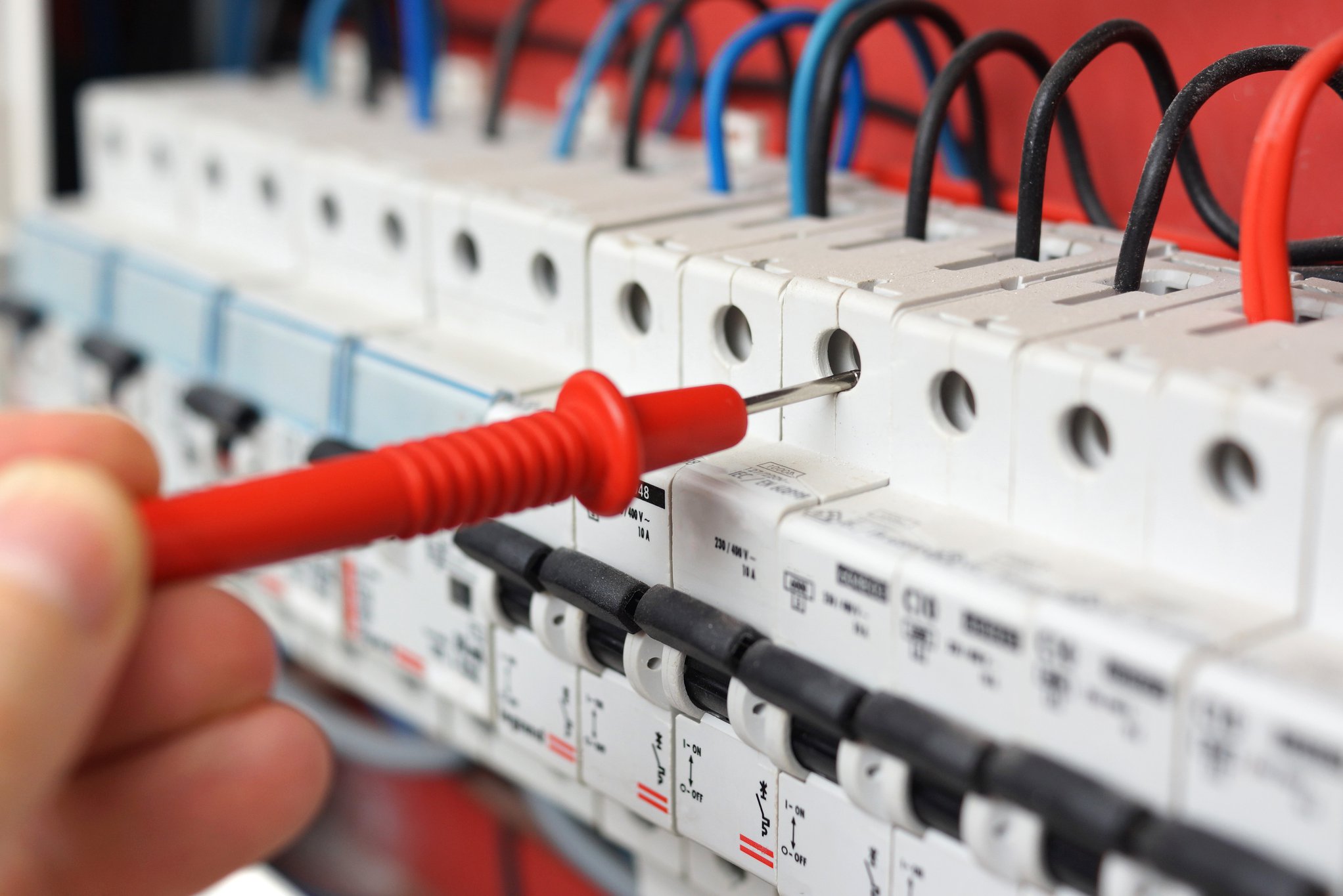 stock-photo-hand-of-an-electrician-with-multimeter-probe-at-an-electrical-switchgear-cabinet-174082043.jpg